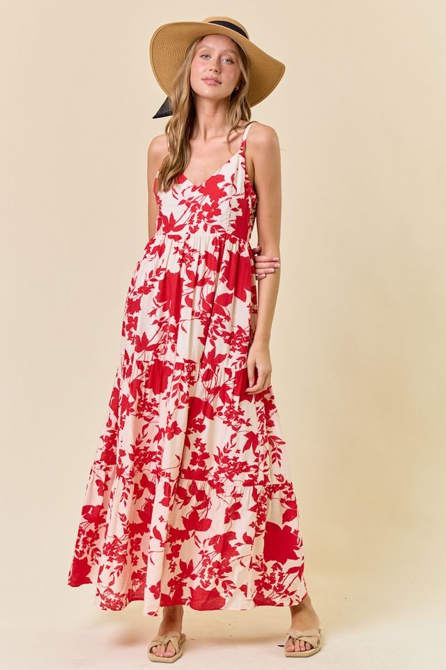 woman wearing a red and white floral maxi dress with thin straps and a wide-brimmed hat