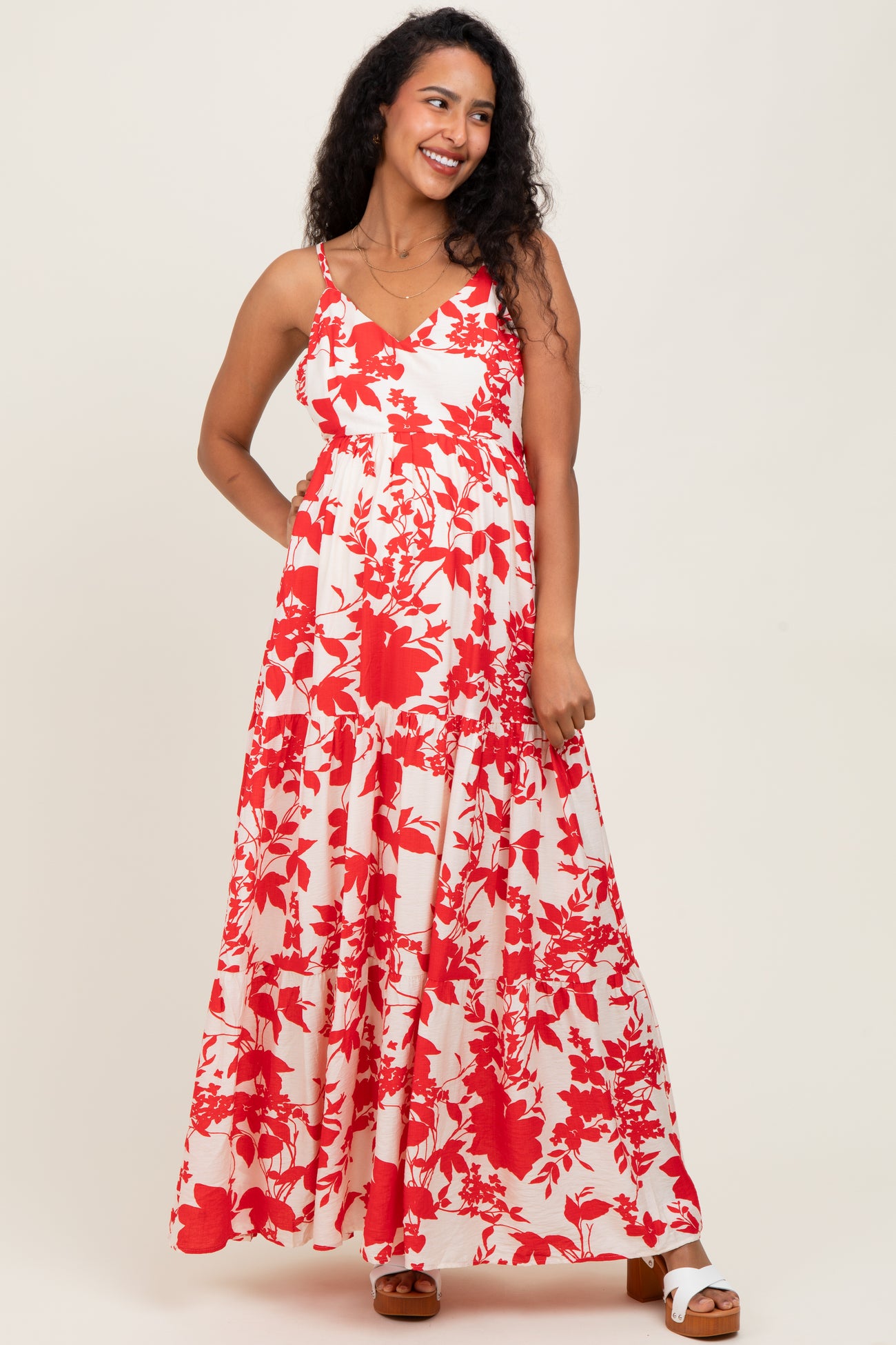 woman wearing a red and white floral maternity maxi dress with a tiered skirt and adjustable straps