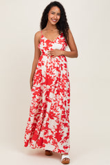 woman wearing a red and white floral maternity maxi dress with spaghetti straps and holding her baby bump