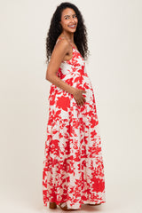 woman wearing a red and white floral maternity maxi dress and holding her baby bump