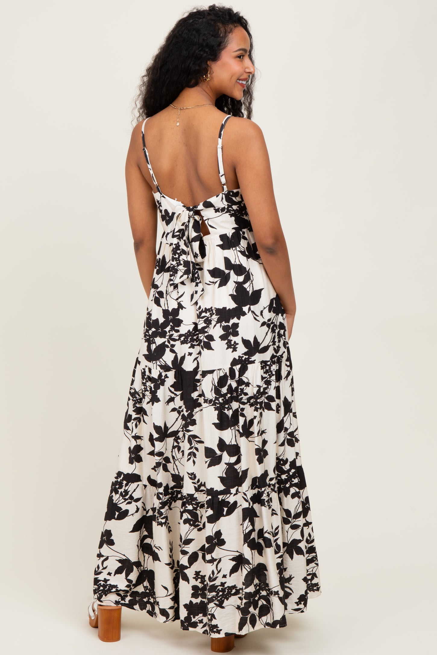 woman wearing a black and white floral maternity maxi dress with a tie back and tiered skirt