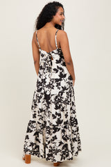 woman wearing a black and white floral maternity maxi dress with a tie back and tiered skirt