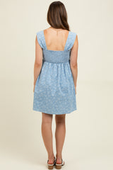 woman wearing a light blue maternity sundress with a smocked back and floral pattern, showing her back