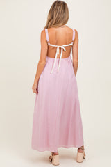 woman wearing a pink backless maternity maxi dress with tie straps, showcasing a flowing silhouette