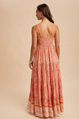 woman wearing a back view of a flowy orange floral maxi dress with smocked bodice and tiered details