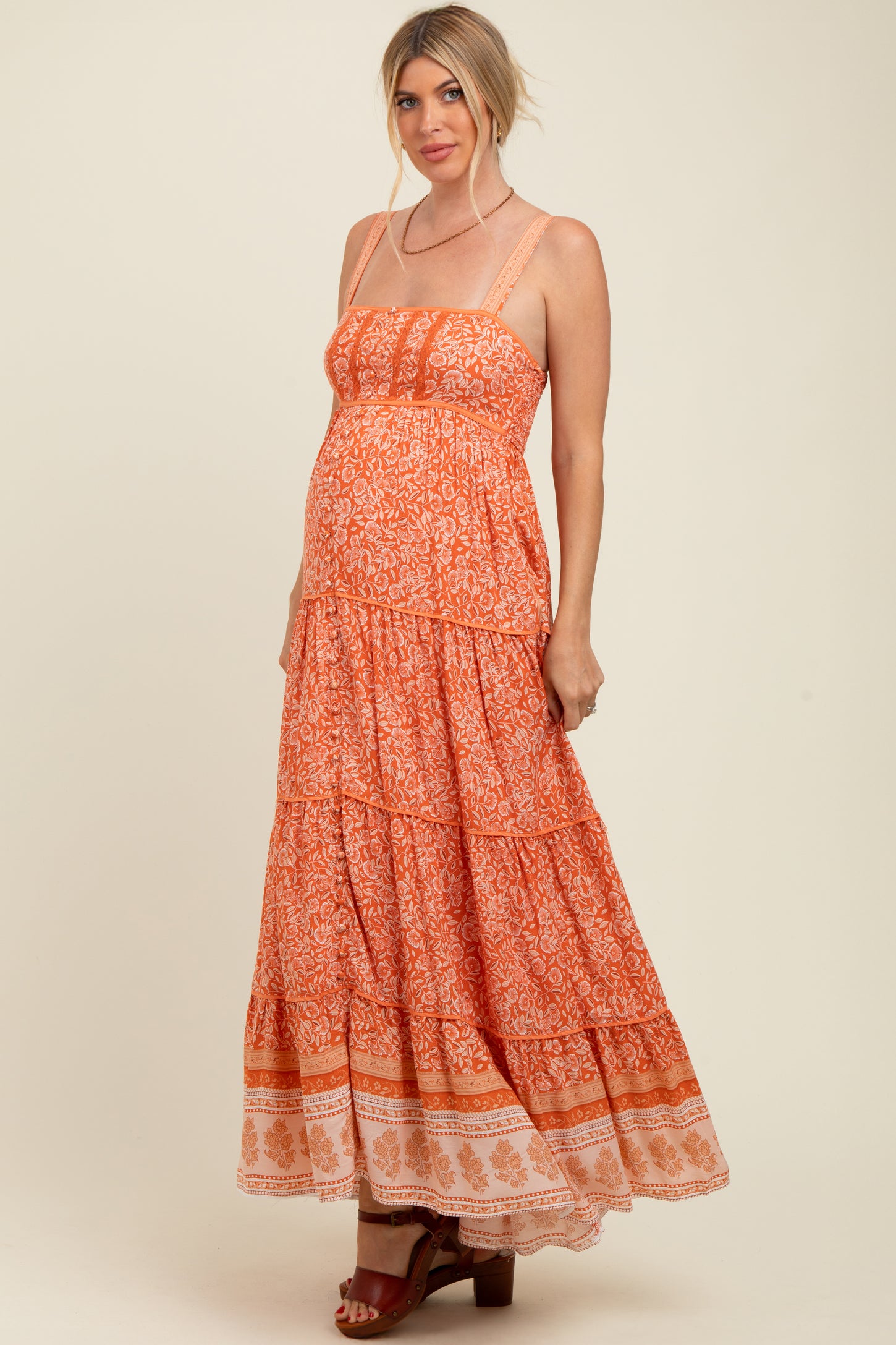 woman wearing an orange tiered maxi maternity dress with spaghetti straps and a visible baby bump
