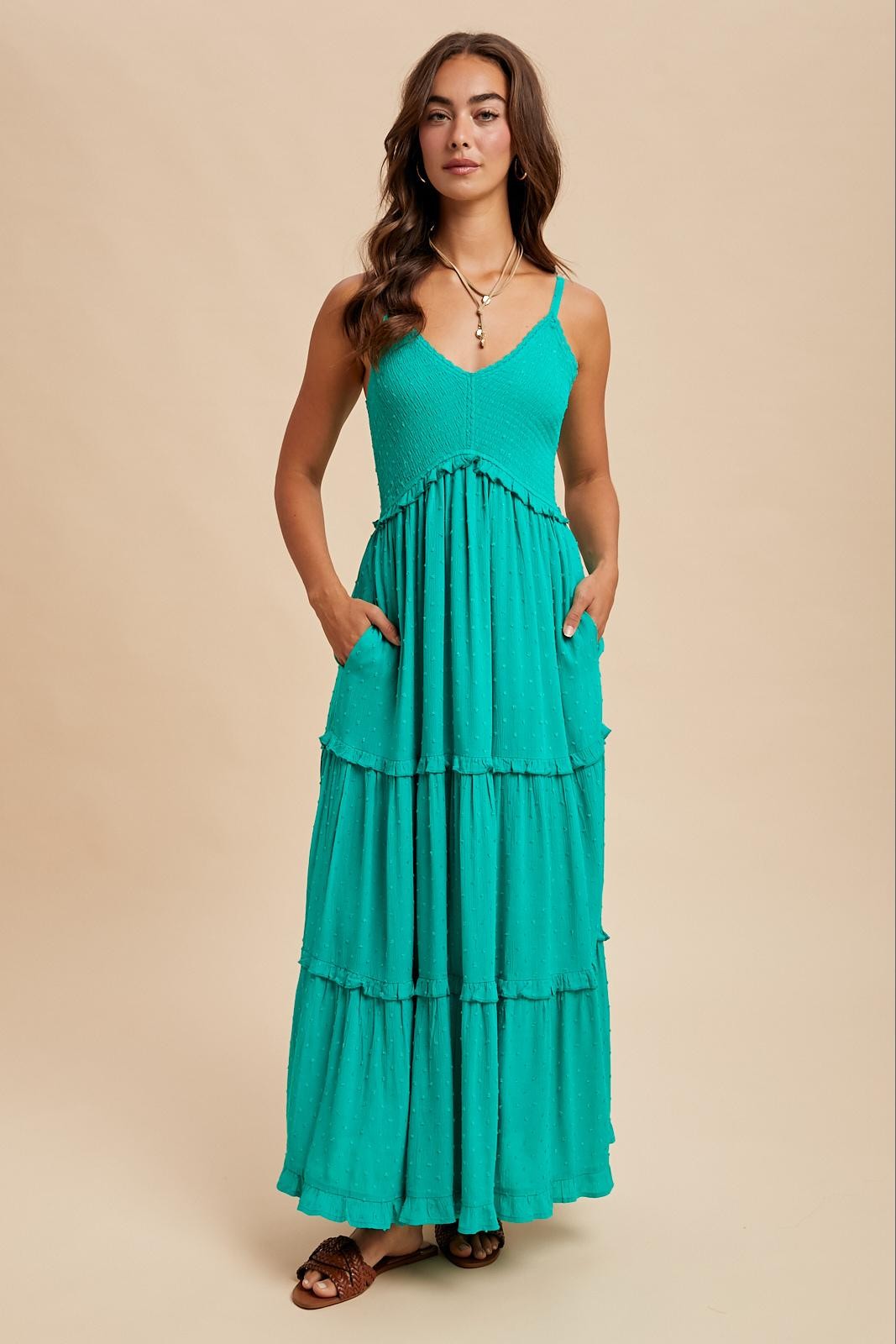 woman wearing a teal tiered maxi dress with adjustable straps and side pockets
