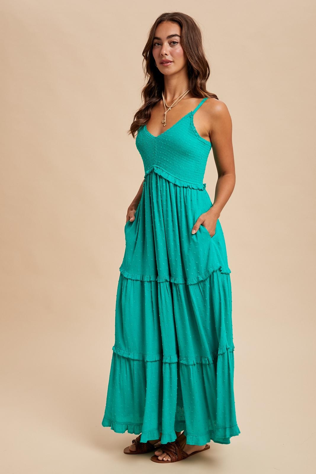 woman wearing a teal tiered maxi dress with adjustable straps and pockets