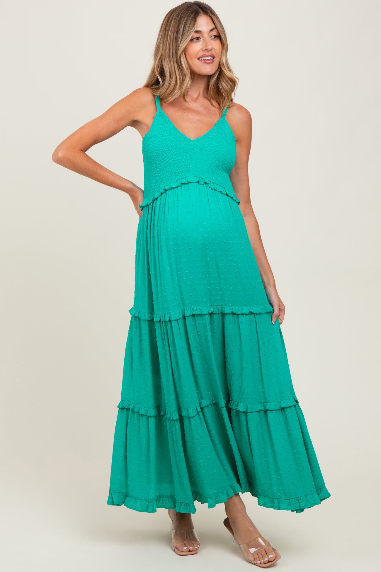 woman wearing a green tiered maternity dress with adjustable spaghetti straps and a visible baby bump