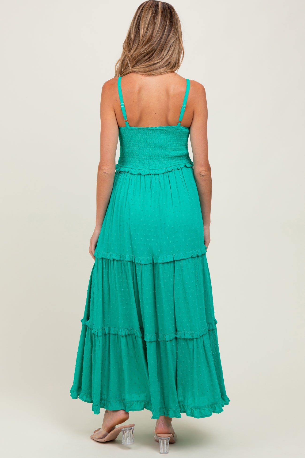 woman wearing a teal maternity maxi dress with a tiered skirt and adjustable straps, showing her back