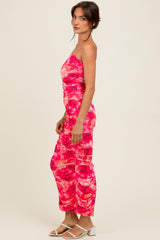 woman wearing a pink and red printed ruched spaghetti strap jumpsuit and white sandals