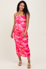 woman wearing a pink tie-dye maternity dress with side ruching and spaghetti straps, showcasing her baby bump