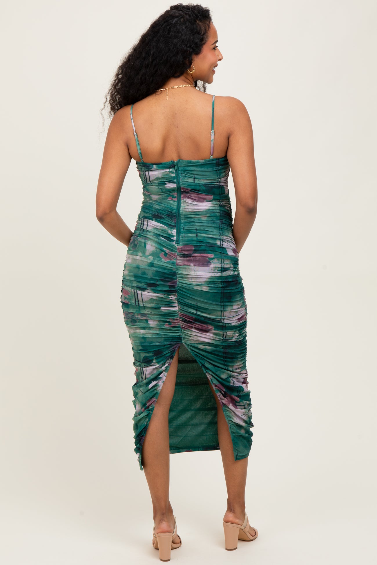 woman wearing a green and purple tie-dye maternity dress with ruching and a side slit, showing her baby bump from the back