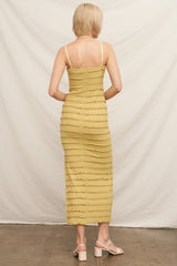 woman wearing a mustard yellow form-fitting midi dress with a textured ruffle design and thin straps