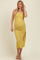 woman wearing a mustard yellow ruched maternity dress with a side slit and spaghetti straps, showcasing her baby bump