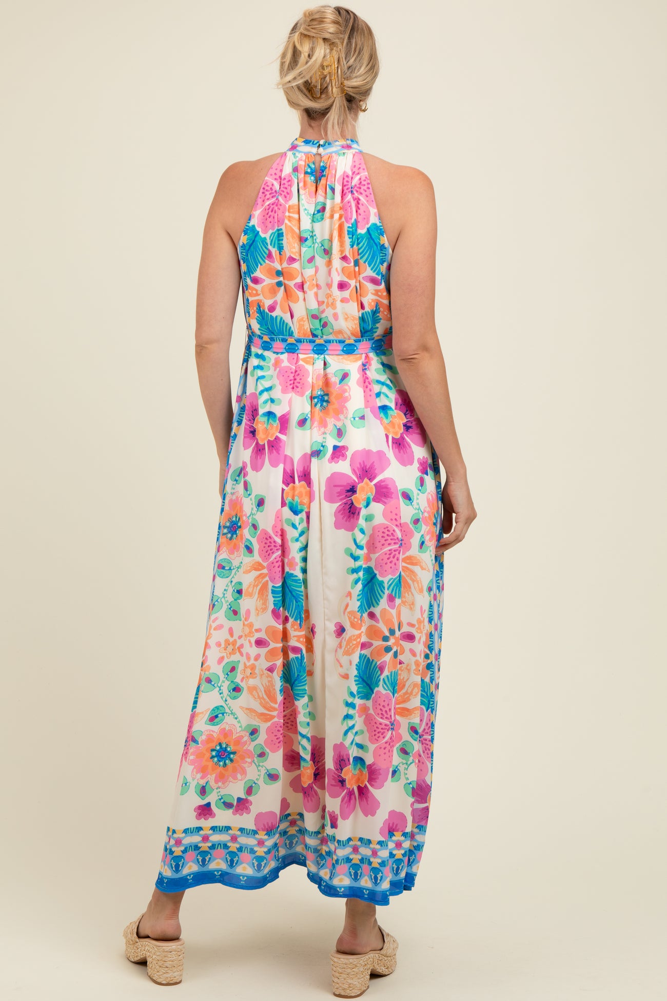 woman wearing a floral print maternity maxi dress with a halter neckline, showing the back view