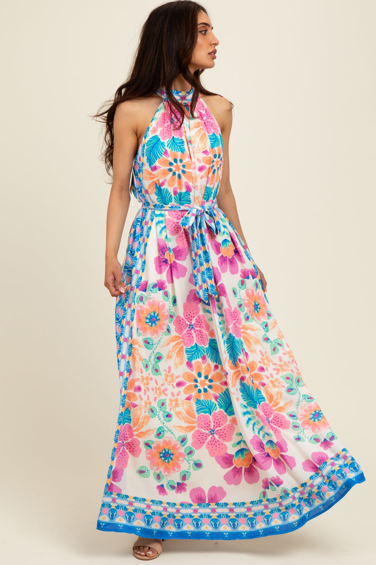 woman wearing a colorful floral maxi dress with a halter neckline and a tied waist detail
