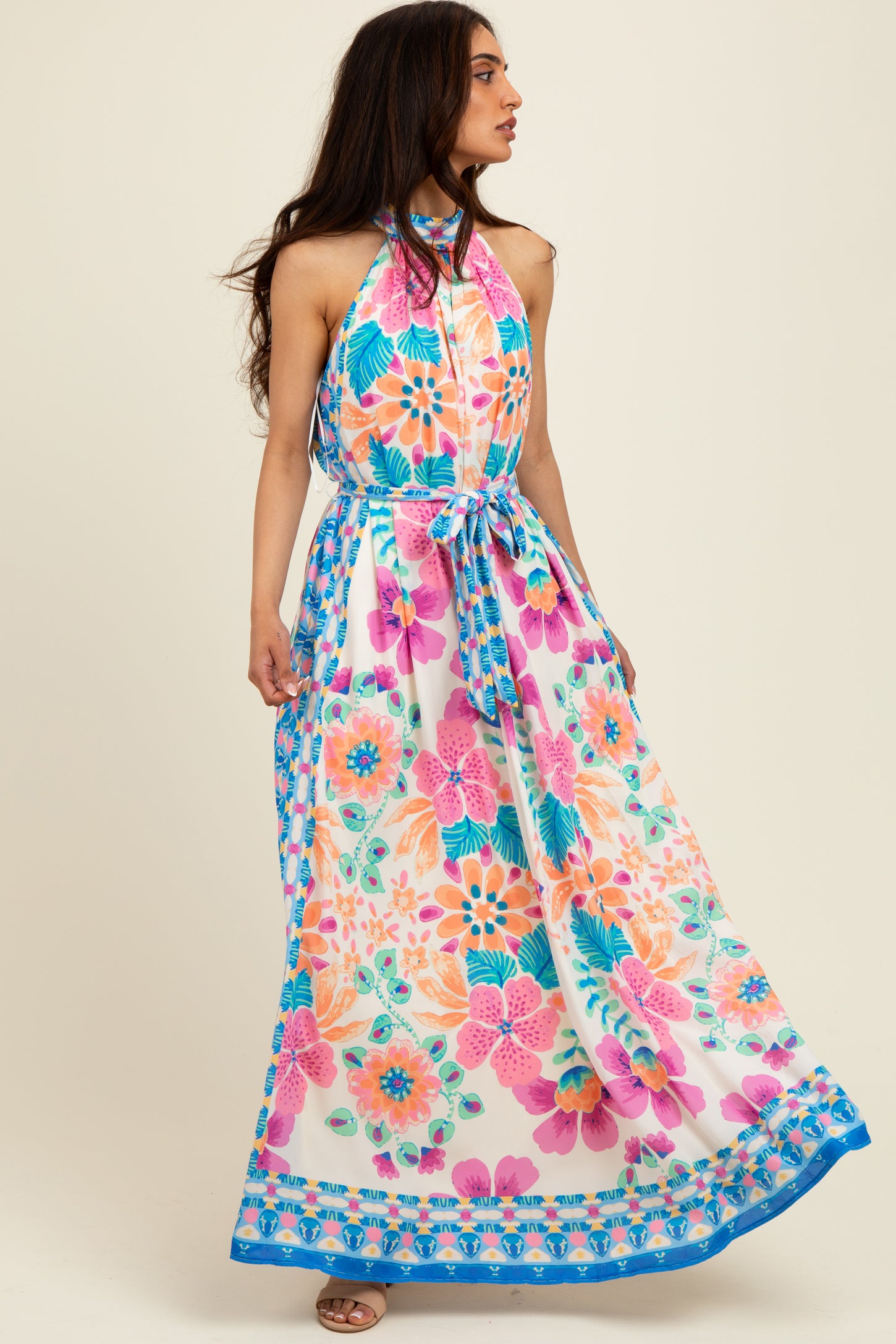 woman wearing a colorful floral maxi dress with a halter neckline and a tied waist detail