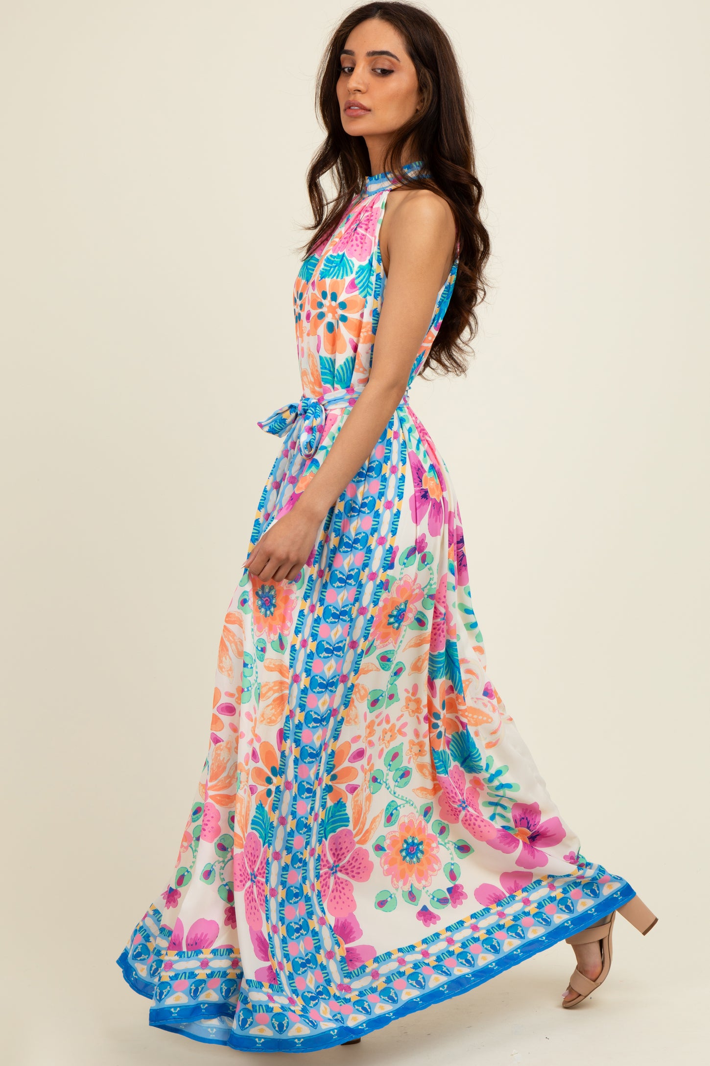 woman wearing a colorful floral maxi dress with a tie waist and a flowing skirt