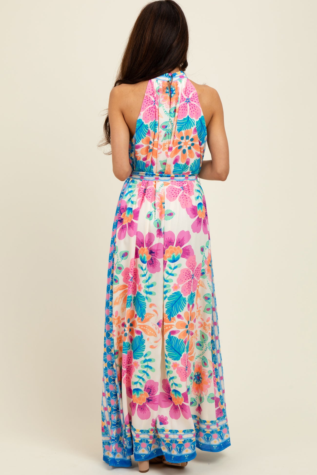 woman wearing a back view of a colorful floral long maxi dress with halter neck and open back style