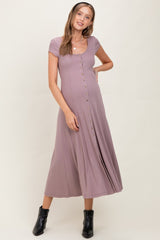 woman wearing a mauve short sleeve maternity dress with button details and a flowy skirt, showing off her baby bump