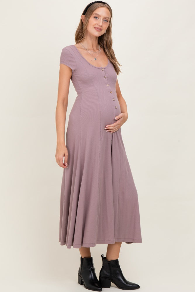 woman wearing a mauve short sleeve maternity dress with buttons and holding her baby bump