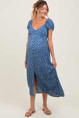 woman wearing a blue maternity dress with white polka dots and a front slit, gently showcasing her baby bump