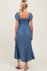 woman wearing a blue polka dot maternity dress with a smocked bodice and puff sleeves, showing a visible baby bump