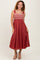 woman wearing a rust-colored maxi dress with embroidered bodice and flowing skirt, smiling and posing