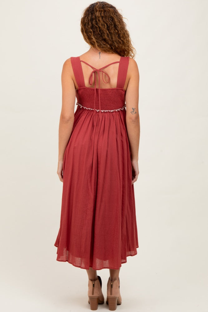 woman wearing a rust red midi dress with a smocked back and spaghetti straps
