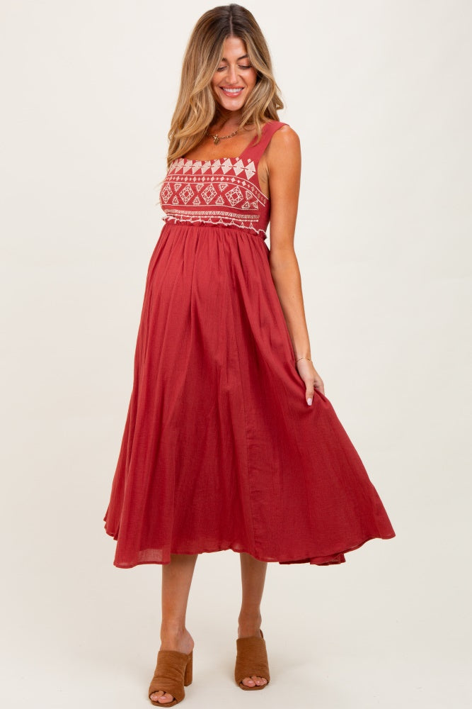 woman wearing a red maternity maxi dress with embroidered details and a visible baby bump
