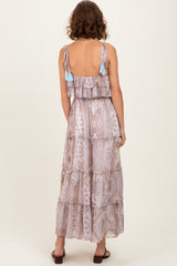 woman wearing a backless tiered maxi dress with a paisley print and tassel detailing on the straps