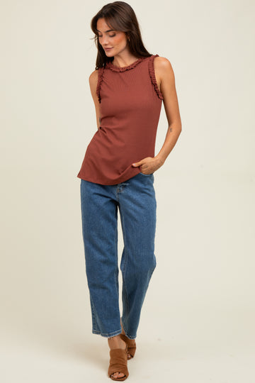 woman wearing a rust sleeveless top with ruffle detailing, paired with high-waisted blue jeans and brown heeled sandals