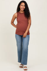 woman wearing a rust-colored maternity tank top with ruffle details and blue wide-leg jeans, showing her baby bump
