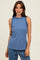 woman wearing a blue sleeveless top with ruffle details and a round neckline