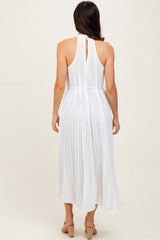 woman wearing a white pleated midi dress with a halter neckline and keyhole back detail