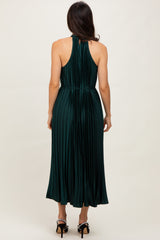woman wearing a dark green pleated midi dress with a halter neck and open back