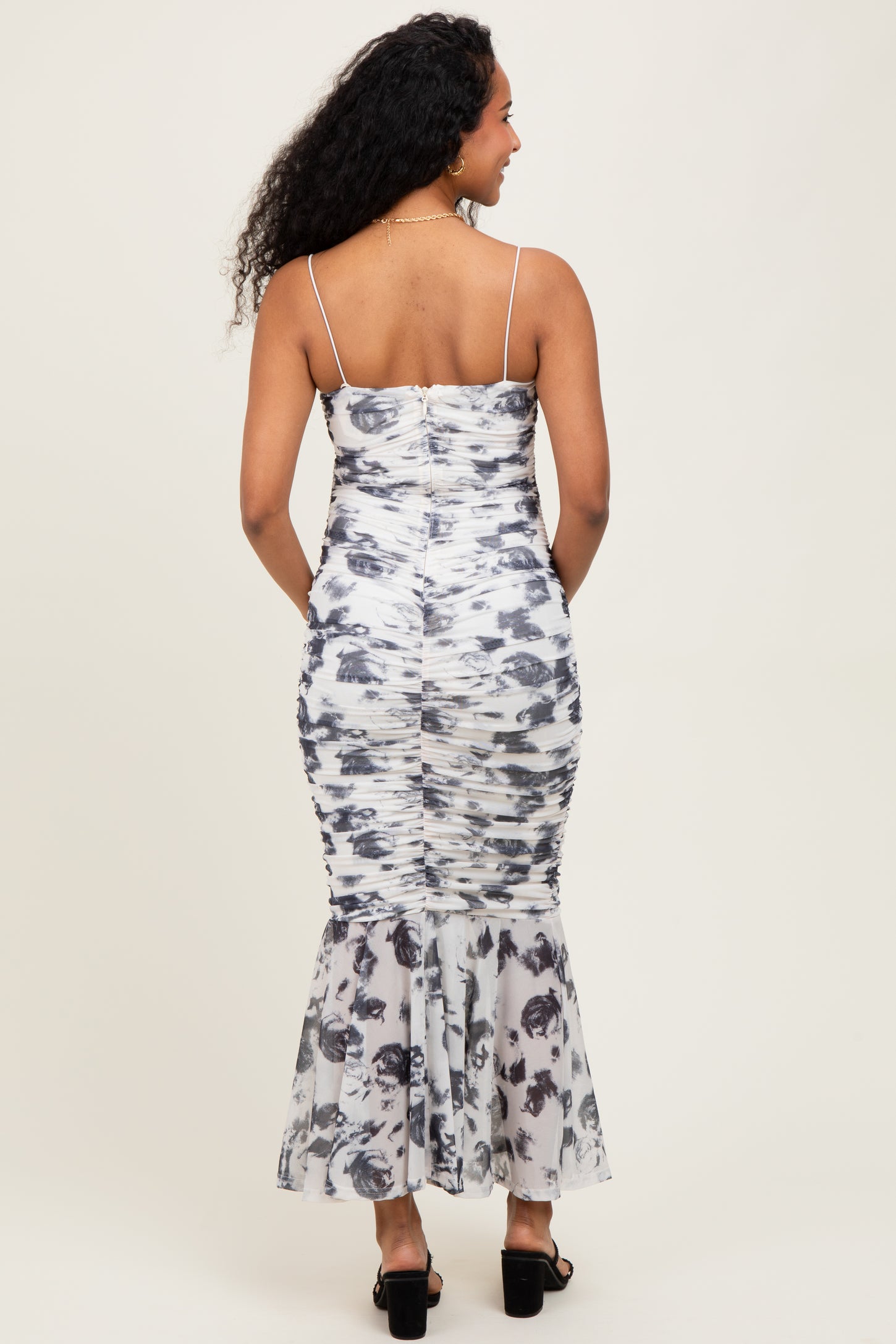 woman wearing a floral print maternity dress with a fitted bodice and flared skirt, showing off a baby bump from behind