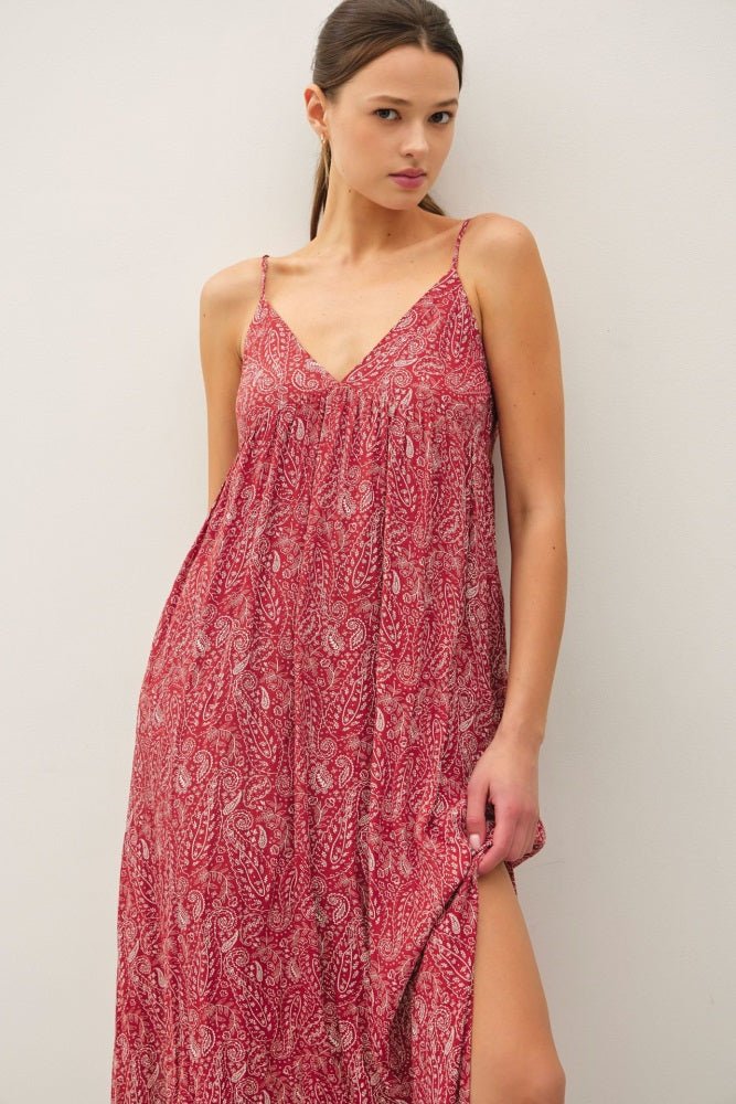 woman wearing a red paisley maxi dress with spaghetti straps and a high side slit