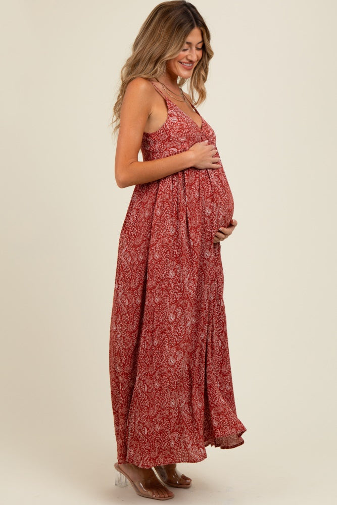woman wearing a red floral print maternity maxi dress and holding her baby bump