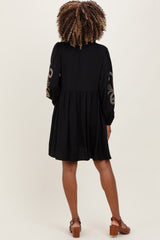 woman wearing a black maternity dress with decorative sleeves and a loose fit, showcasing a flowing silhouette from the back