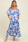 woman wearing a blue and white floral maternity maxi dress with puff sleeves and pockets, featuring a baby bump