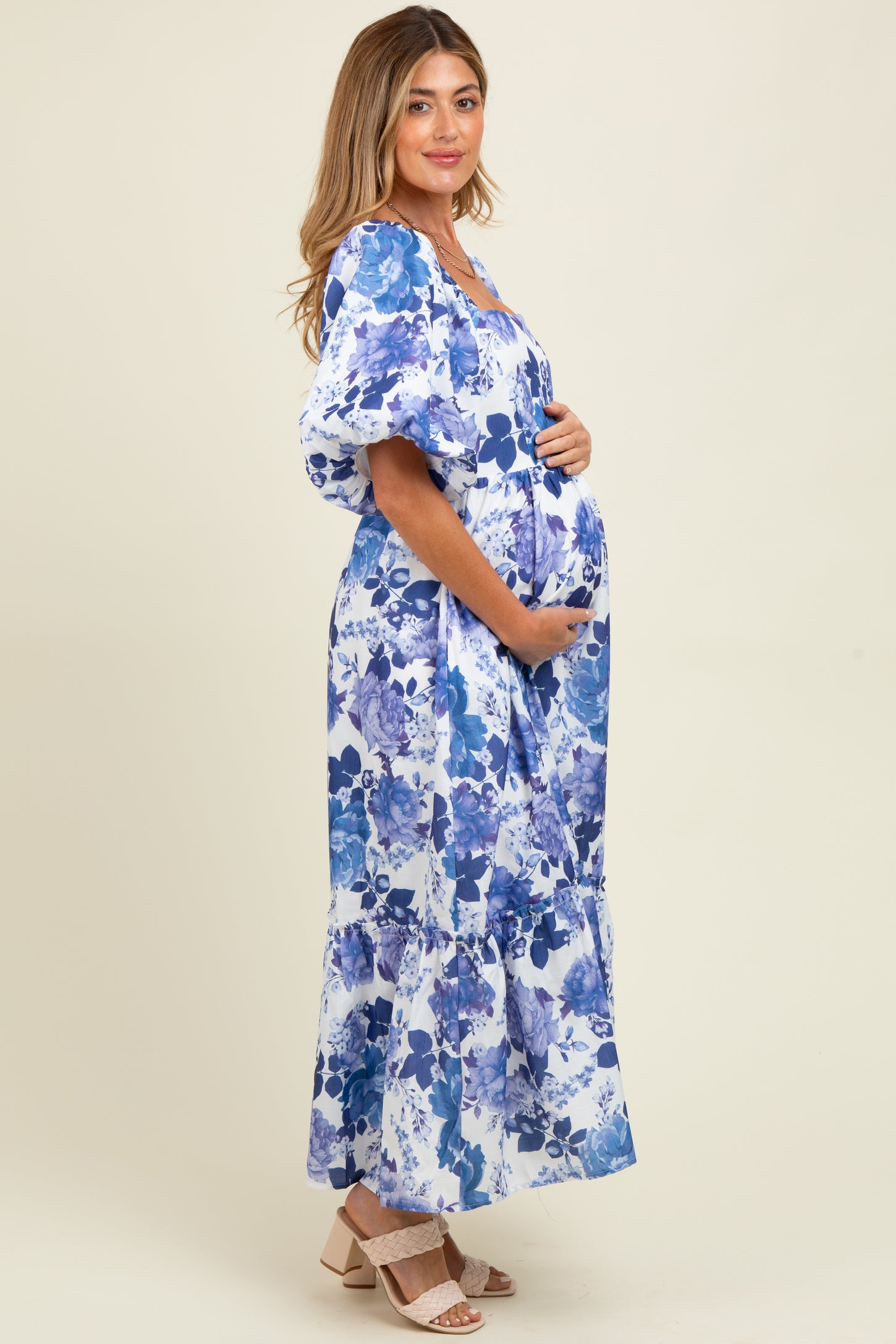 woman wearing a floral print blue and white maternity maxi dress and holding her baby bump