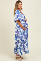 woman wearing a floral print blue and white maternity maxi dress and holding her baby bump