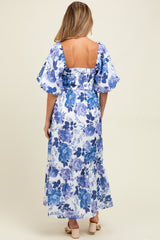 woman wearing a maternity maxi dress with a blue floral print and puff sleeves, showing a beautiful back design
