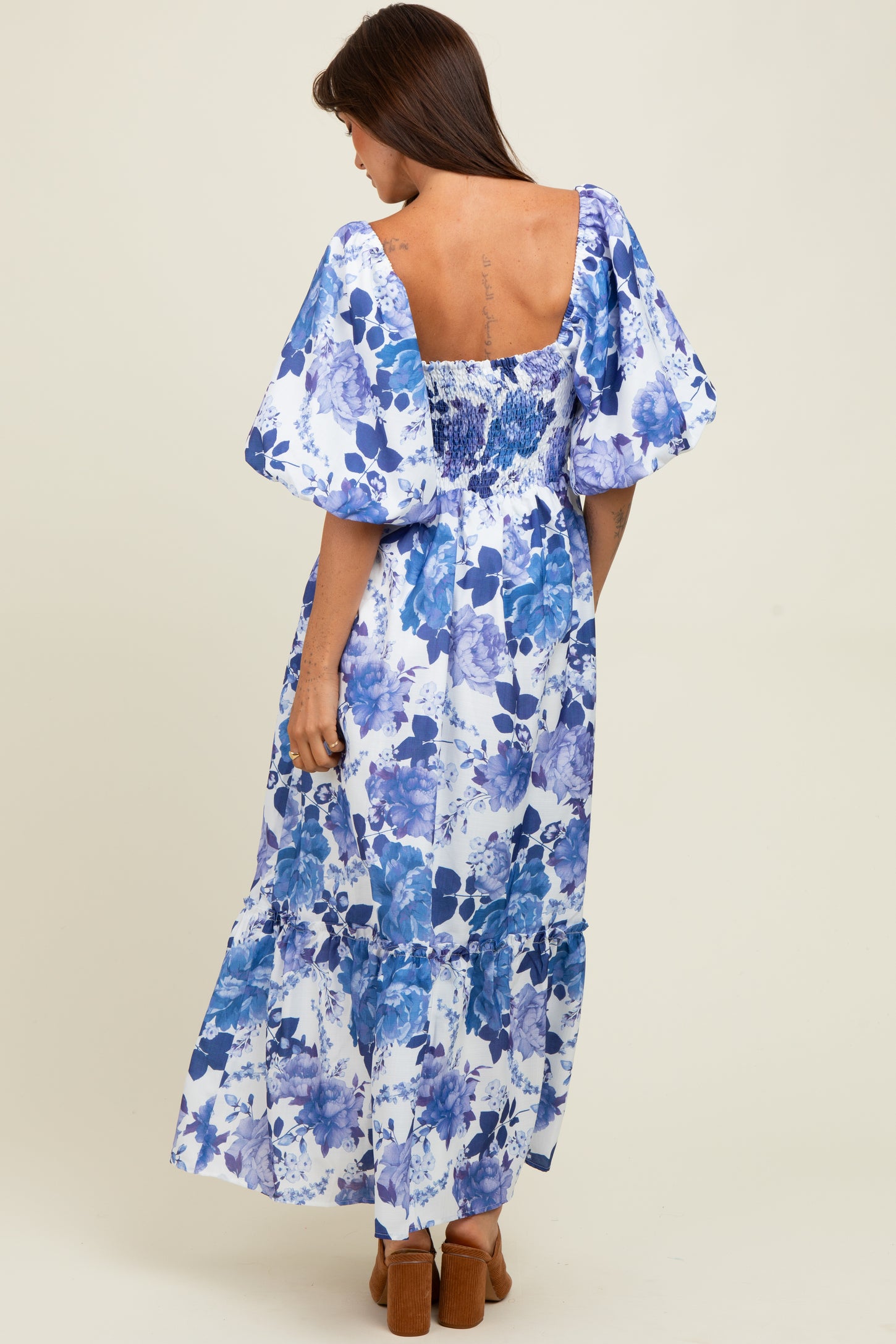 woman wearing a blue floral off-the-shoulder maxi dress with puff sleeves and a ruffled hem