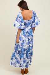 woman wearing a blue floral off-the-shoulder maxi dress with puff sleeves and a ruffled hem