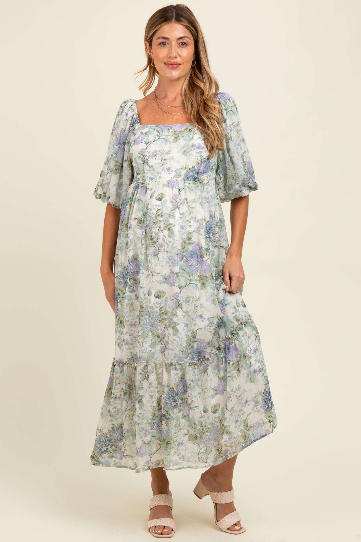 woman wearing a floral maternity maxi dress with puffed sleeves and a square neckline, showcasing her baby bump