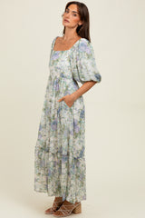 woman wearing a floral maxi dress with a square neckline, puff sleeves, and pockets