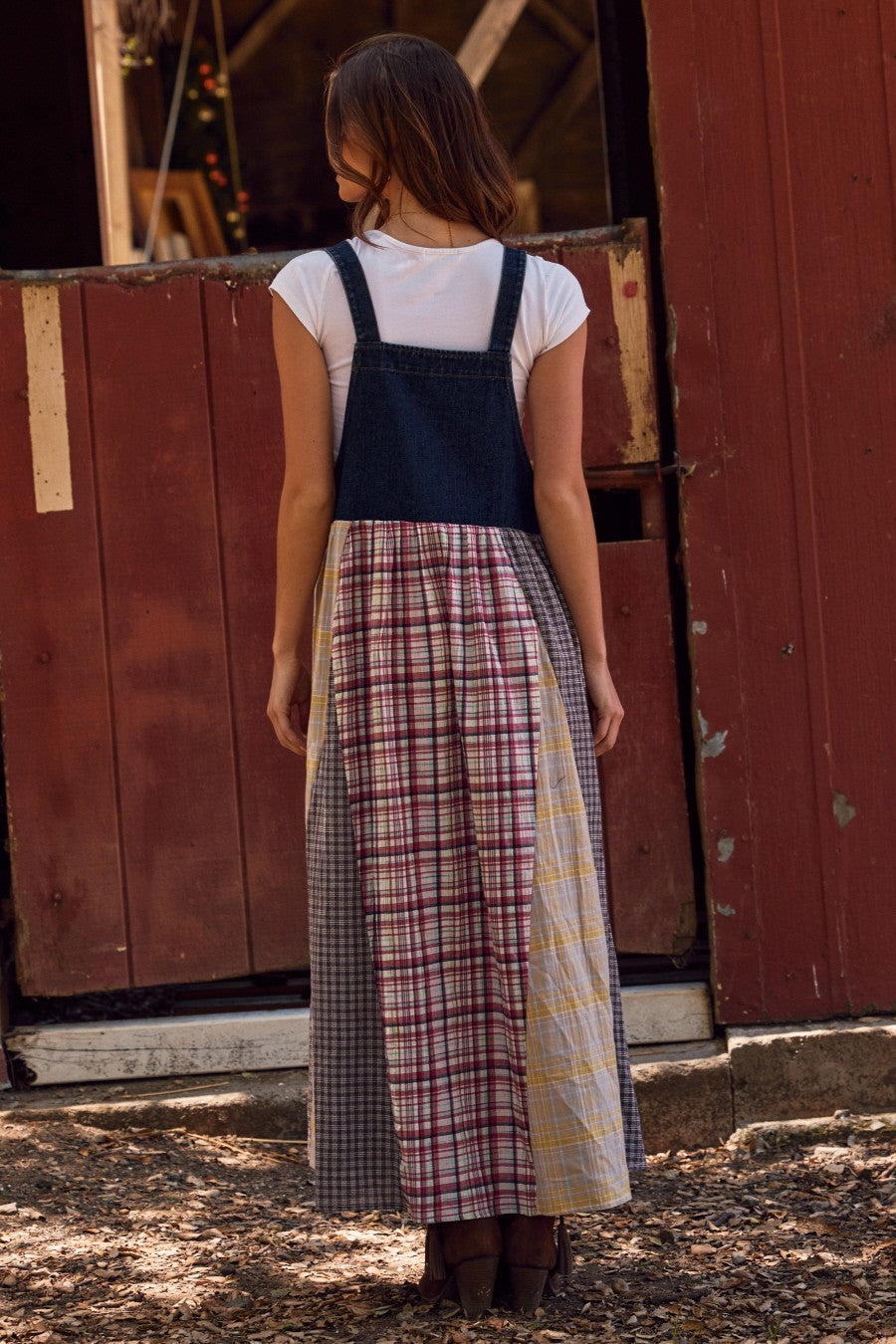 woman wearing a denim strap dress with a patchwork design in plaid and check patterns